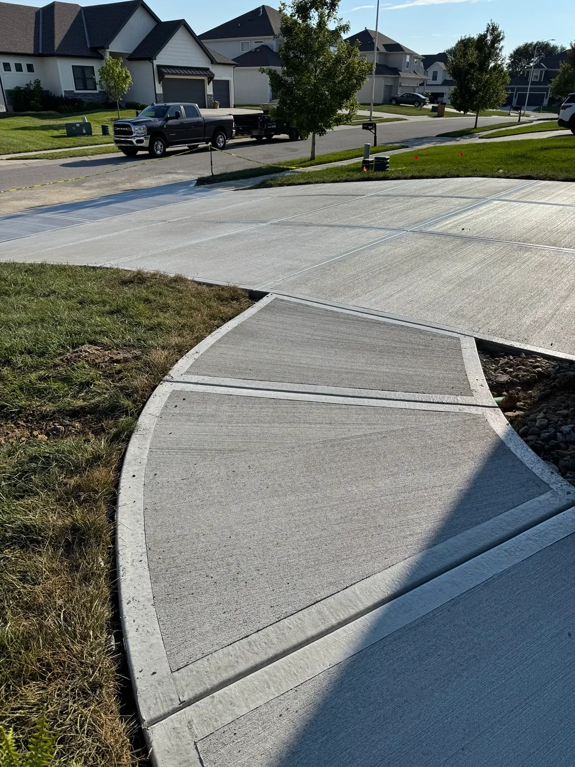 New concrete driveway with curved walkway connection in a residential neighborhood