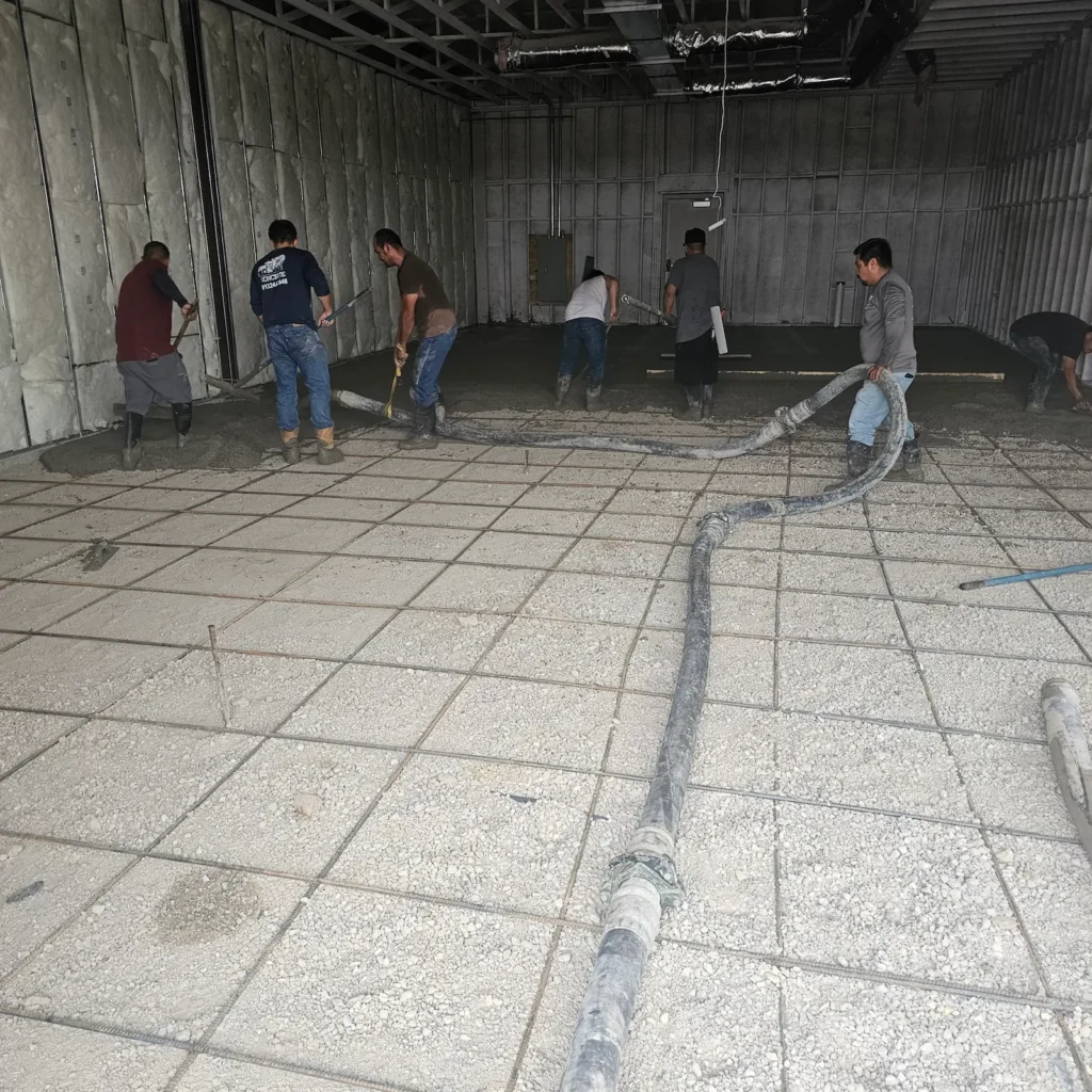 Crew pouring a reinforced interior commercial concrete slab
