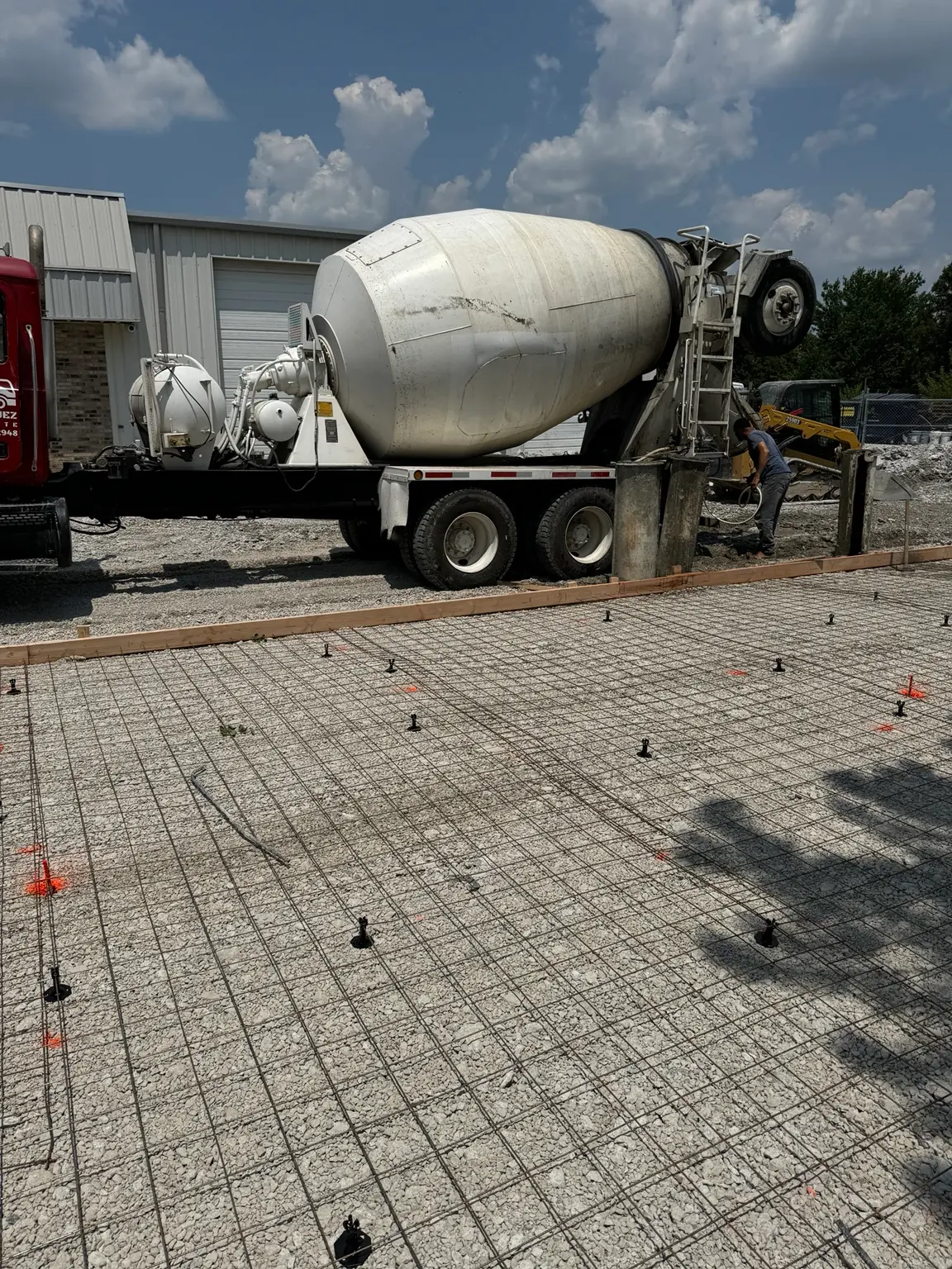 Reinforced commercial concrete slab prepared over aggregate base with ready-mix truck on site